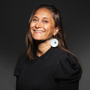 Jaimie Bleck wearing a black shirt and earrings for her headshot 