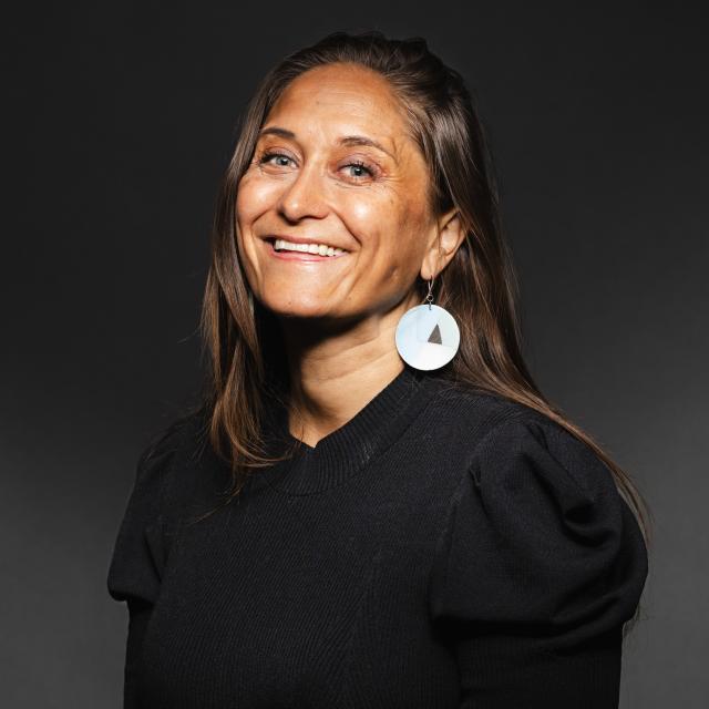 Jaimie Bleck wearing a black shirt and earrings for her headshot